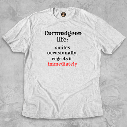 SMILES.™ – And Instantly Regrets It A tee for the man who accidentally showed emotion.